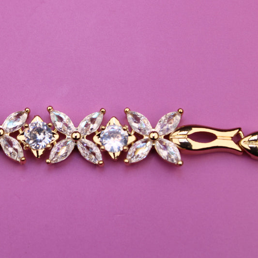 Gold bracelet with clear stones on a pink background