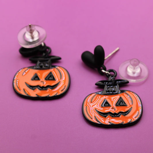Halloween-themed earrings with jack-o'-lantern design on a pink background