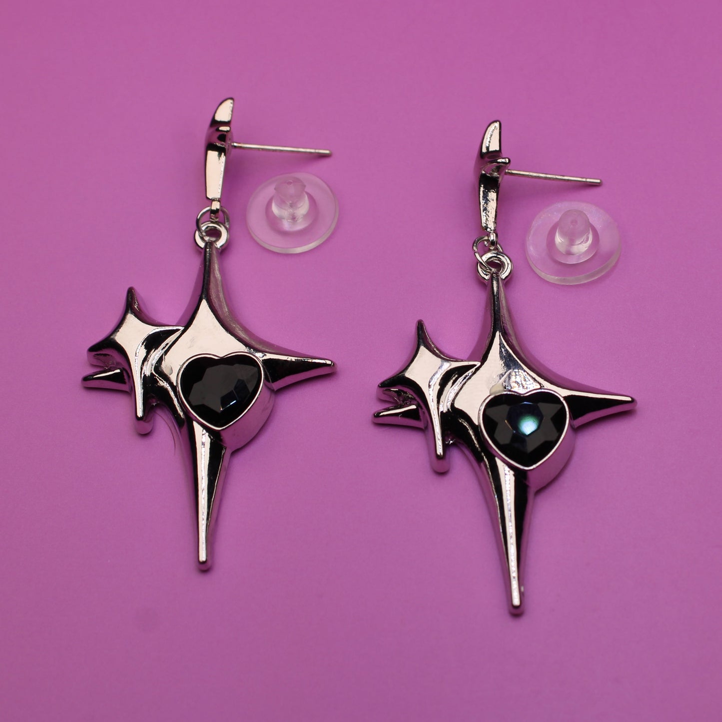 Pair of star-shaped earrings with black centers on a purple background