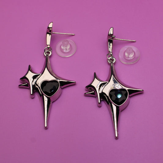 Pair of star-shaped earrings with black centers on a purple background