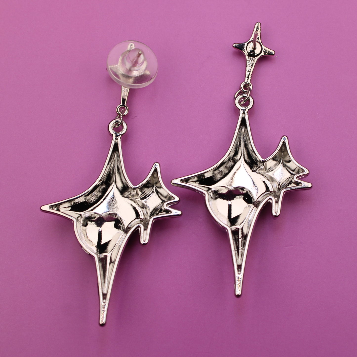 Pair of silver earrings on a purple background