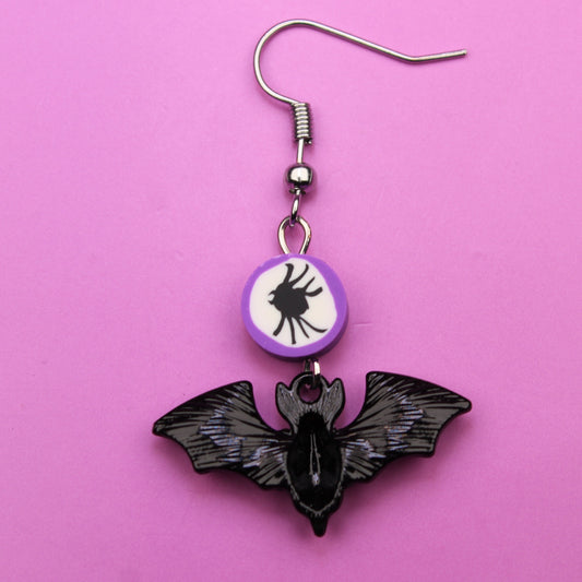 Bat-shaped earring on a pink background
