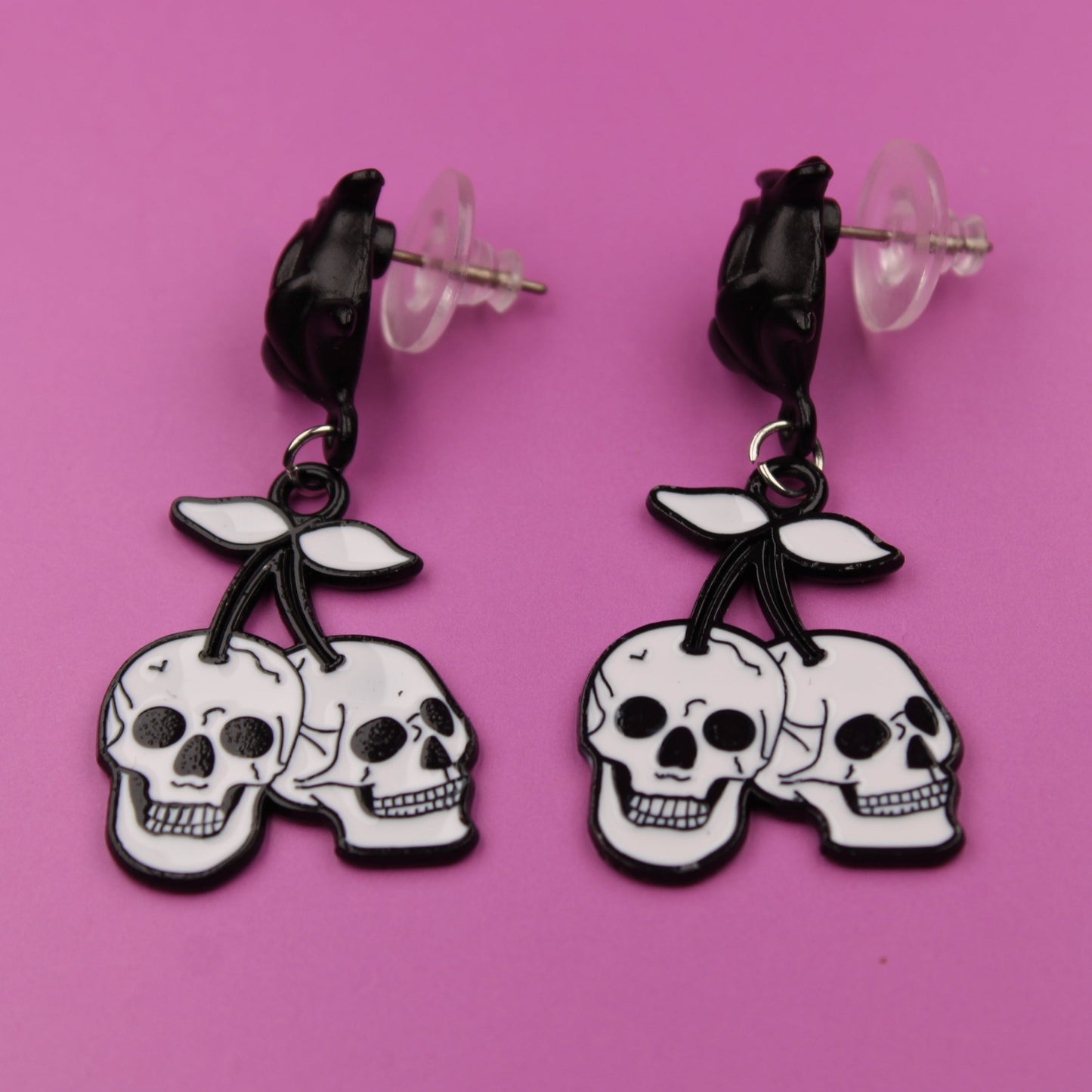 Skull-shaped earrings on a pink background