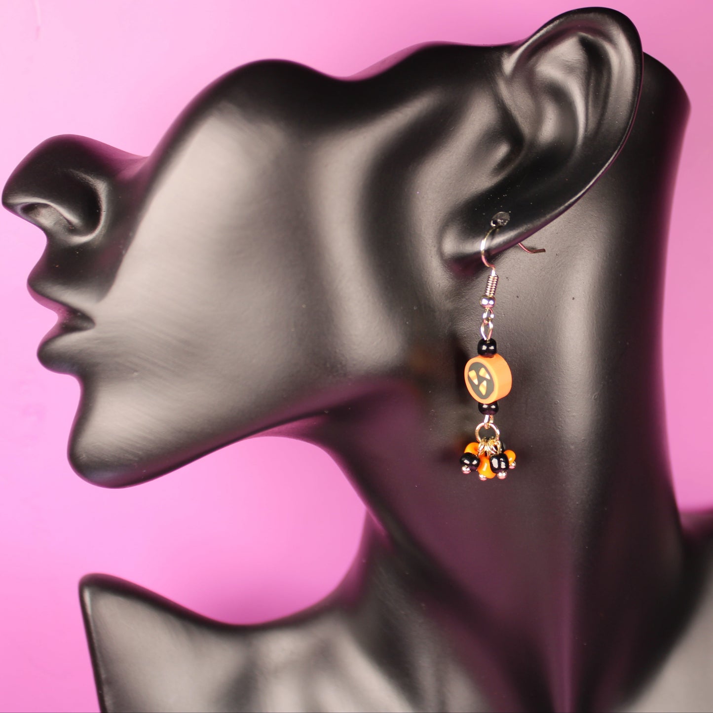 Earrings on a mannequin ear with a pink background