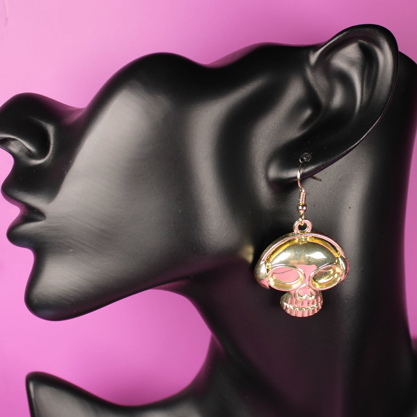 Earring on a black mannequin head with a pink background