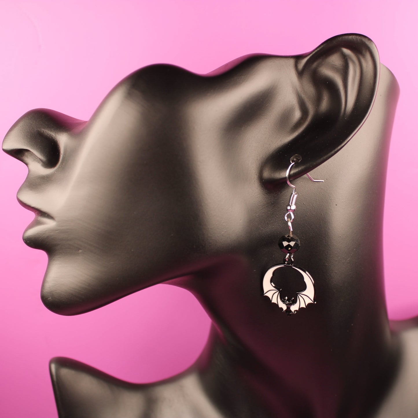 Earring on a mannequin ear against a pink background