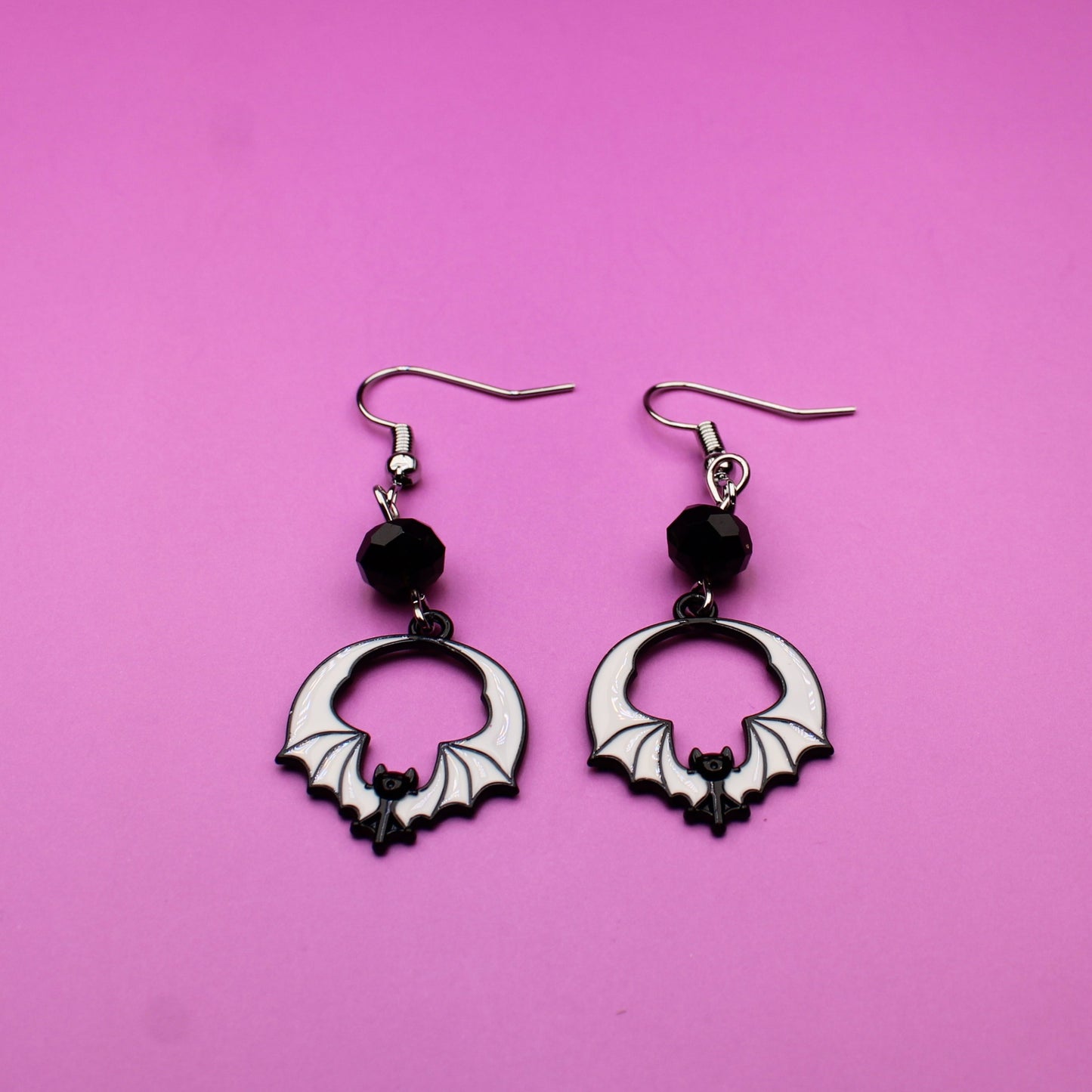 Pair of hoop earrings with black beads on a pink background