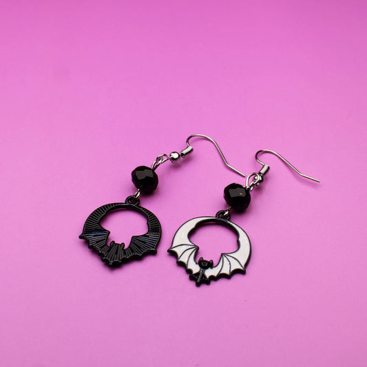 Black and silver earrings on a pink background