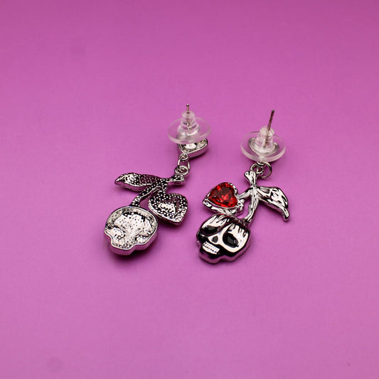 Pair of earrings with decorative charms on a pink background