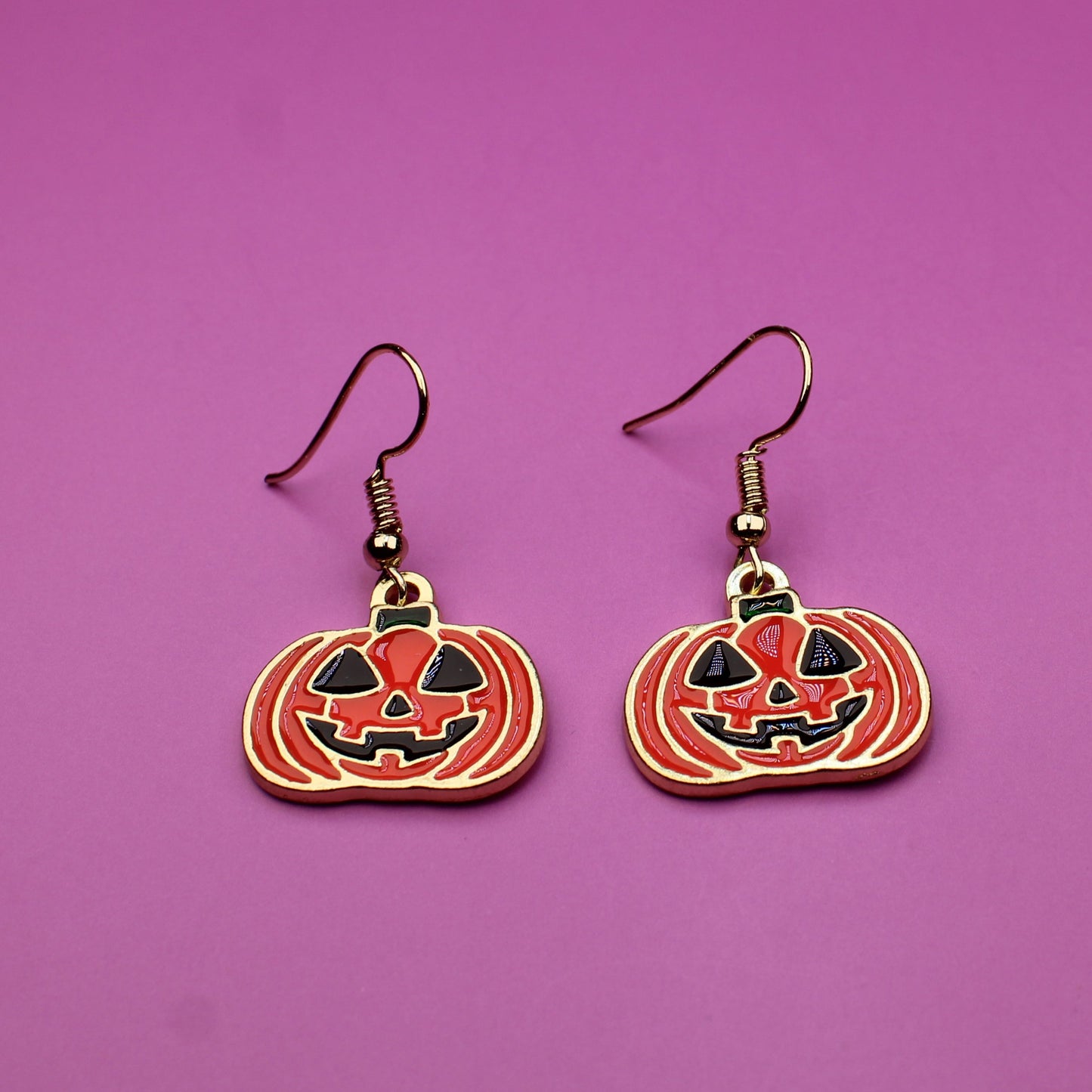 Pumpkin-shaped earrings on a purple background