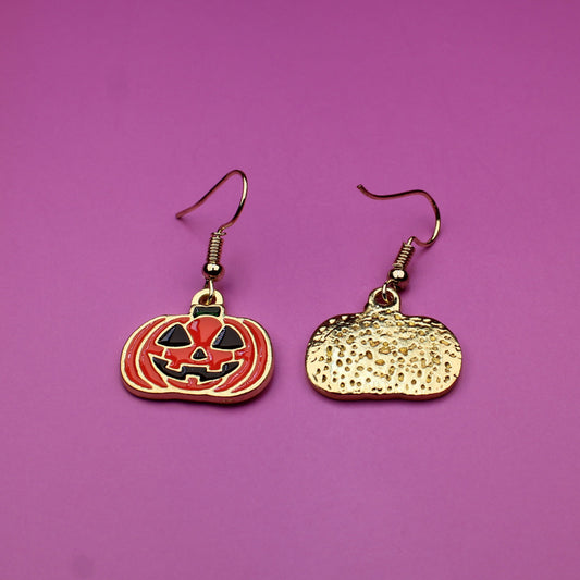 Pumpkin and moon-shaped earrings on a purple background