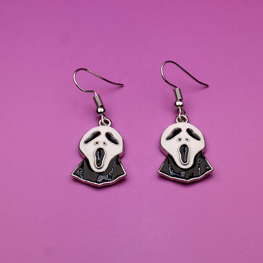 Pair of earrings with a skull design on a pink background