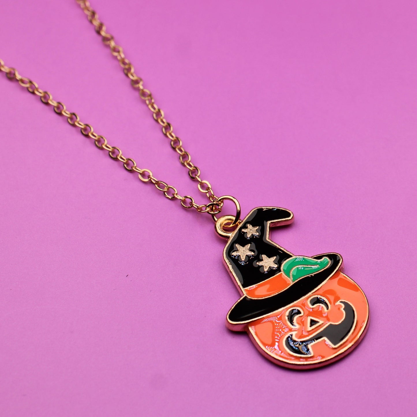 Pumpkin-shaped pendant with a witch on a pink background