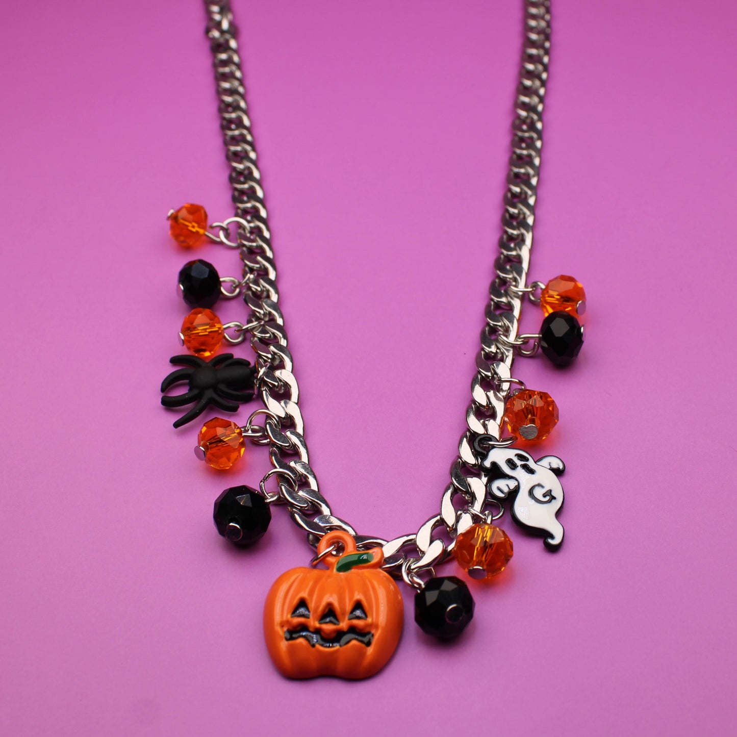 Necklace with Halloween-themed charms on a pink background