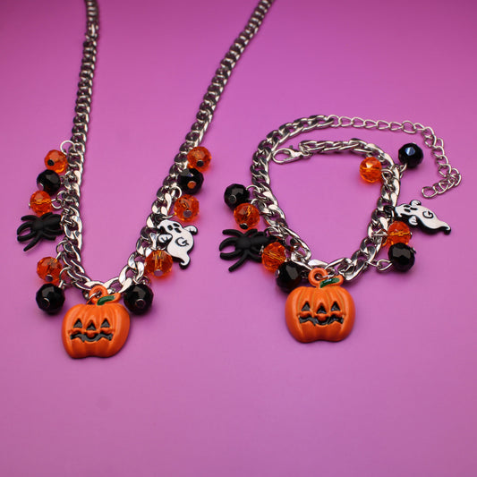 Halloween-themed necklace and bracelet set on a pink background