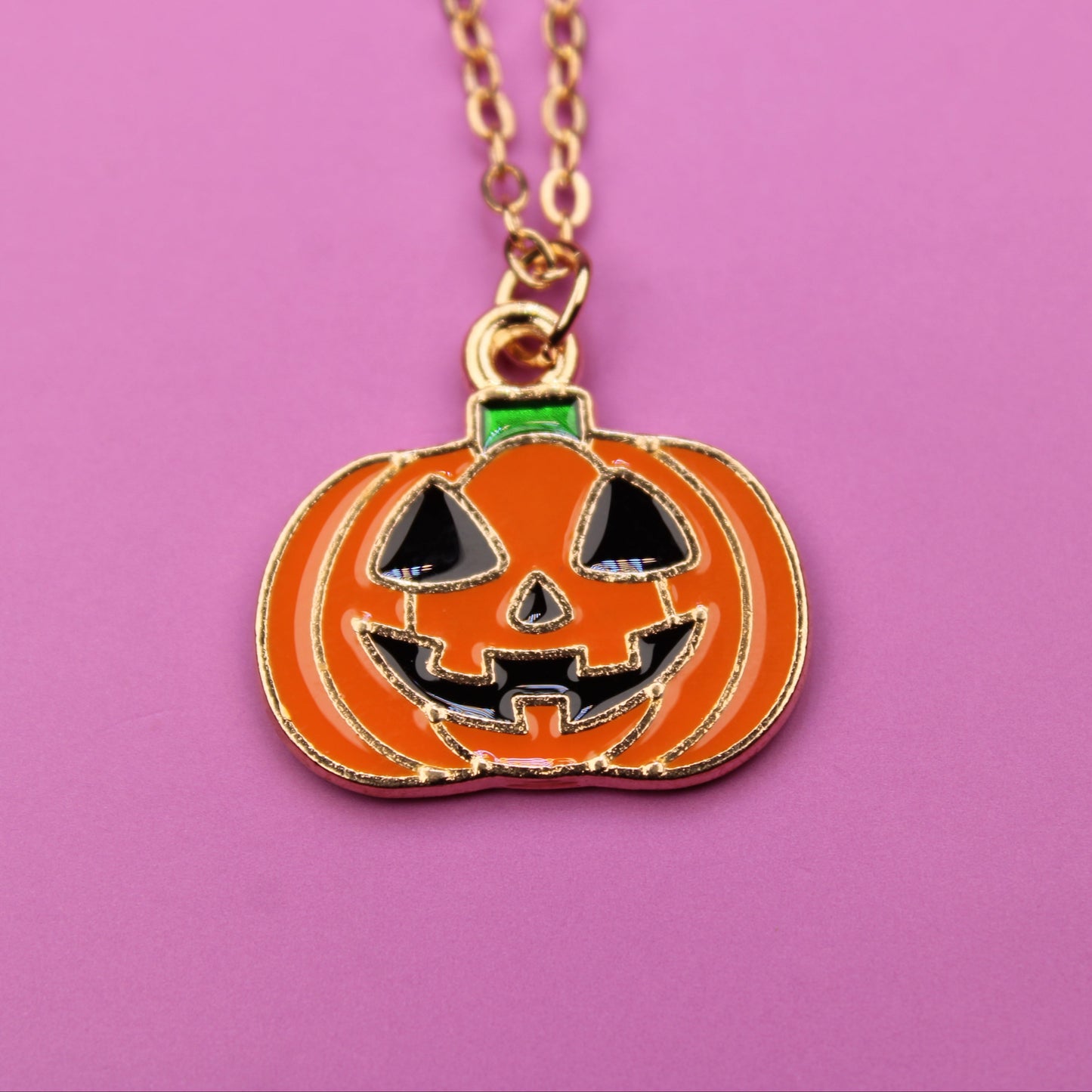 Pumpkin-shaped pendant necklace on a pink background
