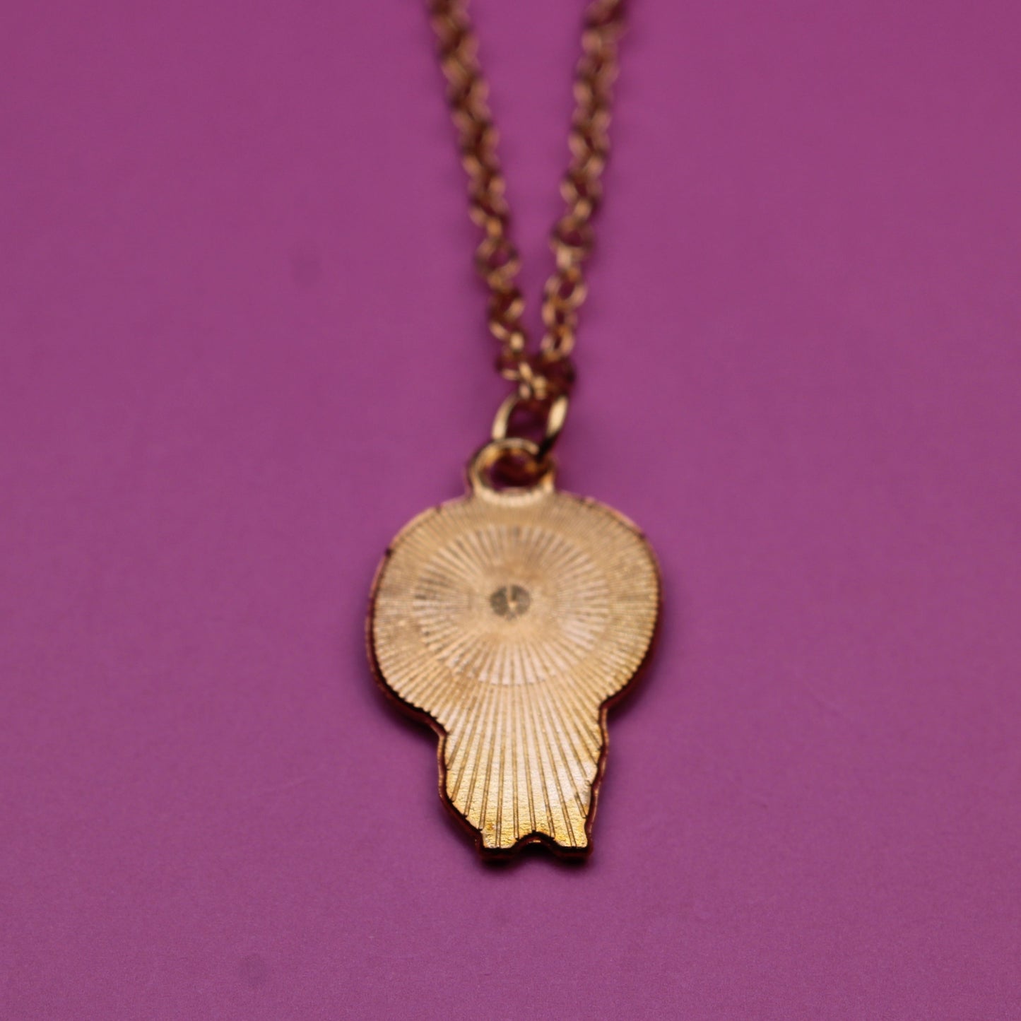 Gold necklace with a pendant on a purple background