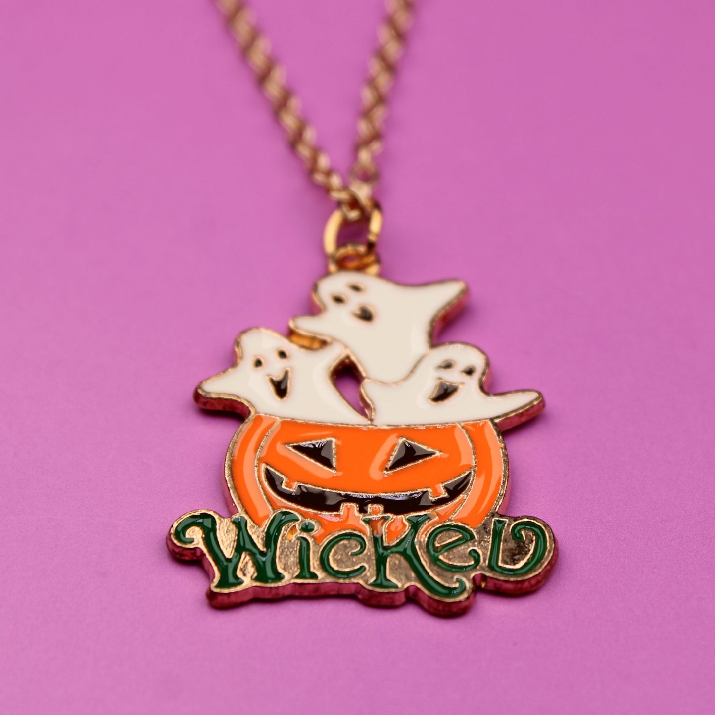 Halloween-themed necklace with pumpkin, ghost, and 'Wicked' text on a pink background