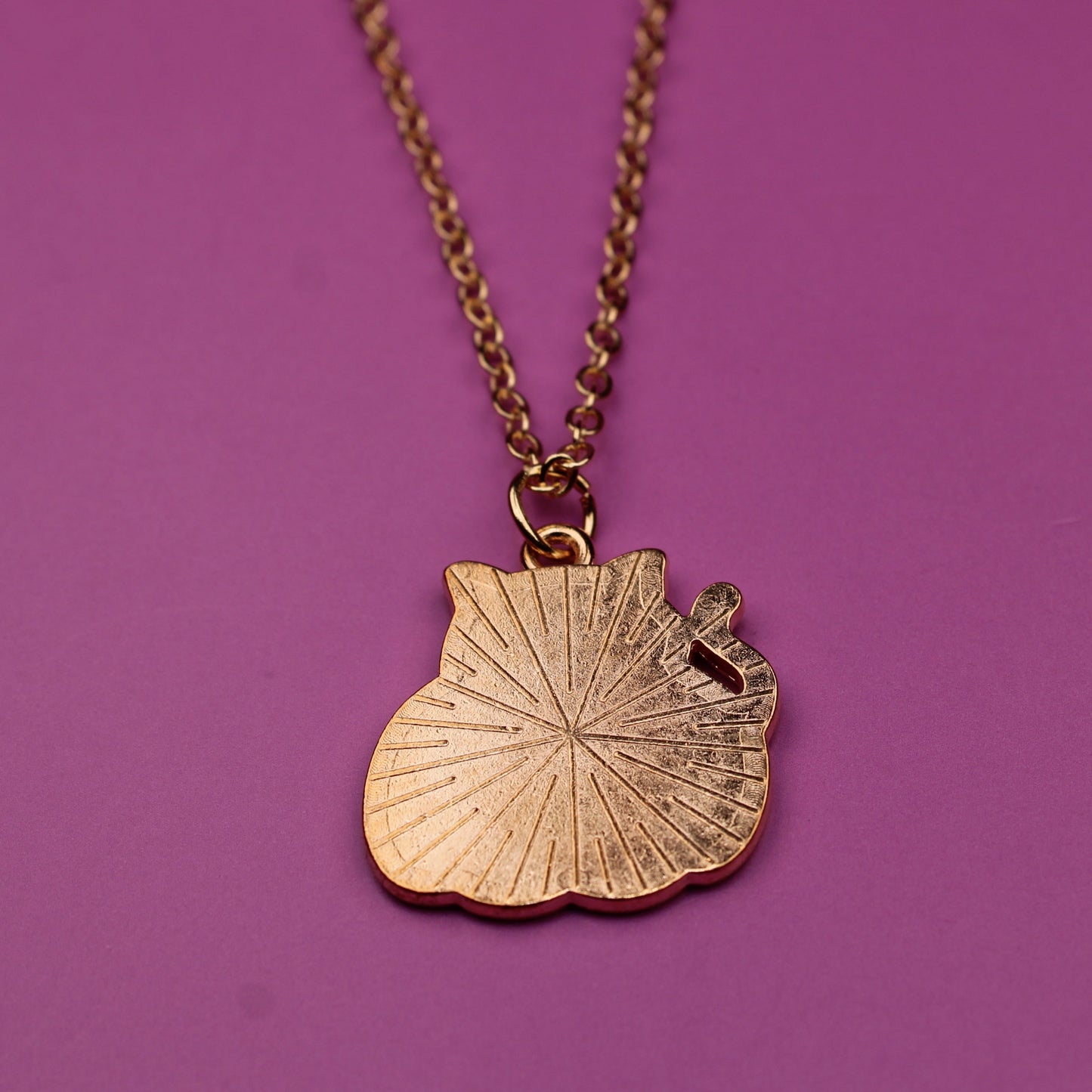 Gold shell pendant necklace on a purple background