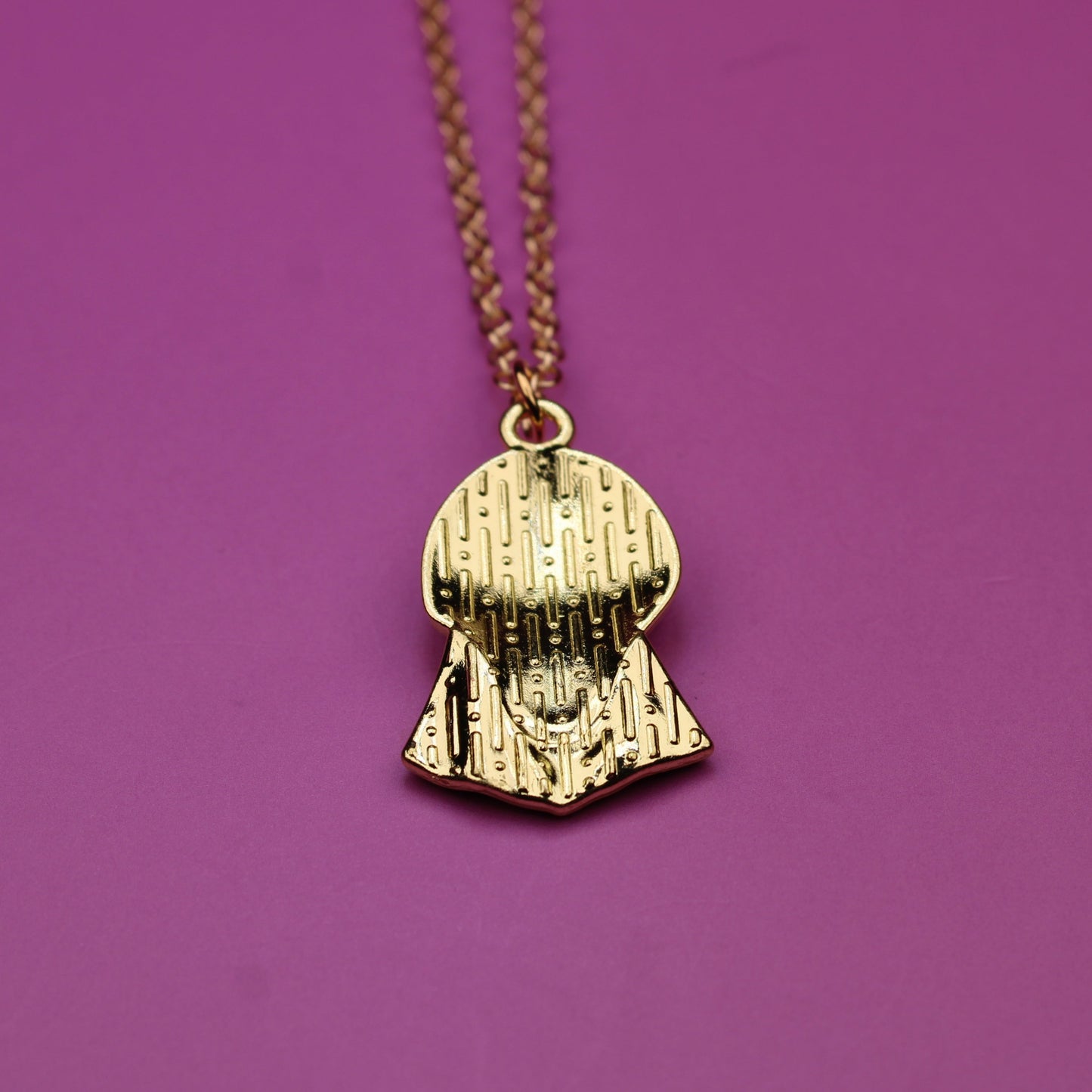 Gold necklace with a pendant on a purple background