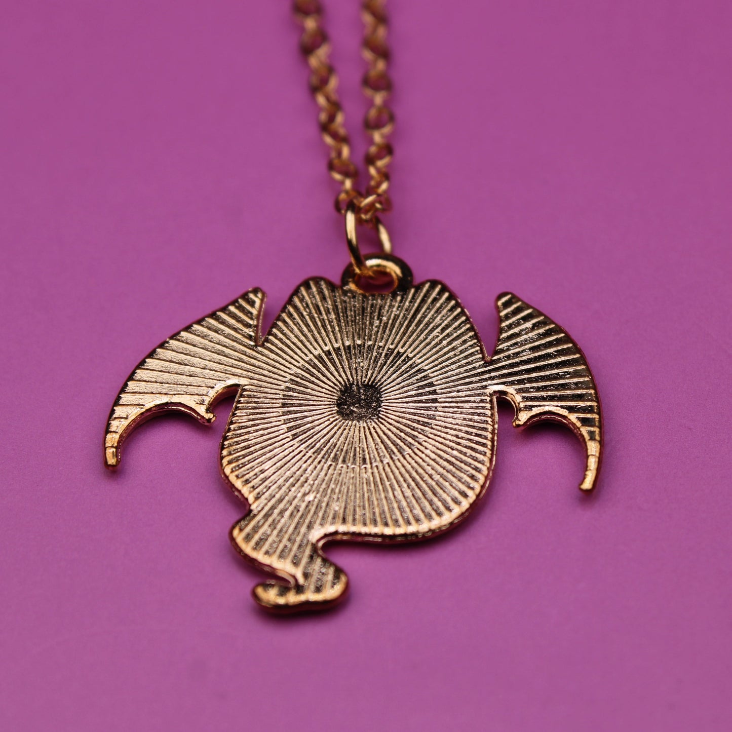 Gold necklace with a unique pendant on a purple background