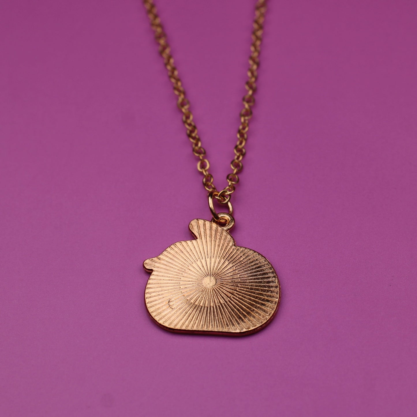 Gold necklace with a shell pendant on a purple background