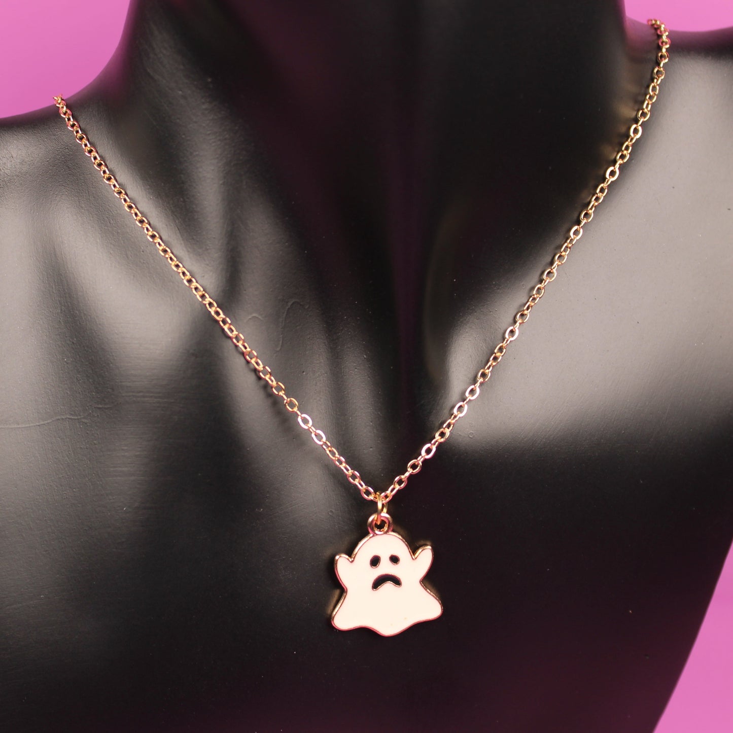 Necklace with a paw print pendant on a black mannequin bust against a pink background