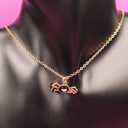 Gold necklace with a pendant on a black mannequin bust against a pink background