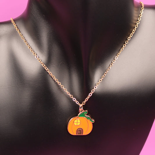 Pumpkin-shaped pendant necklace on a black mannequin bust with a pink background