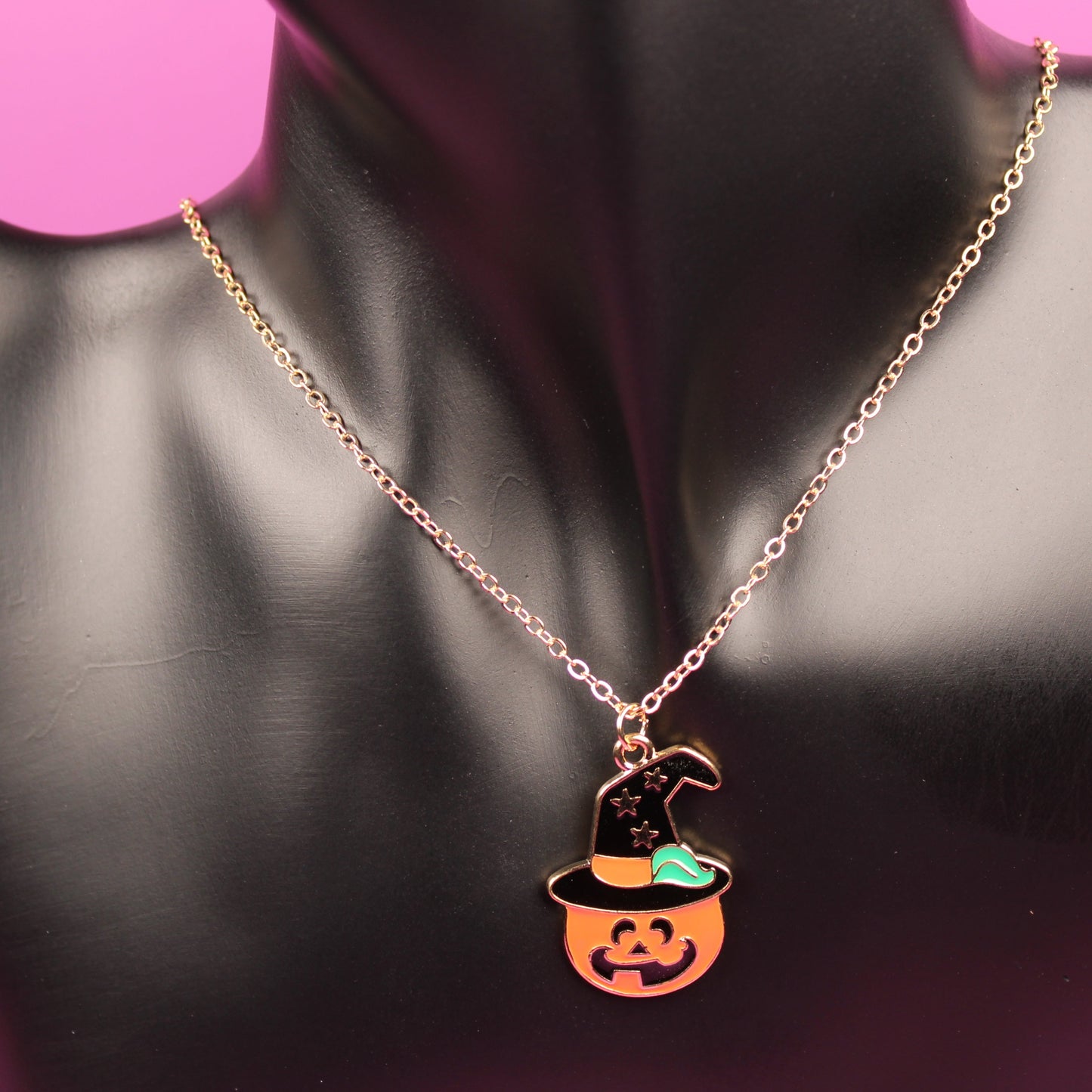 Necklace with a pumpkin pendant on a mannequin bust against a pink background