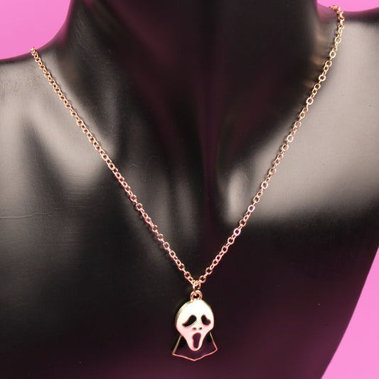 Rose gold necklace with a skull pendant on a black mannequin against a pink background