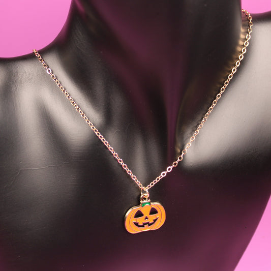 Necklace with a pumpkin pendant on a black mannequin bust against a pink background