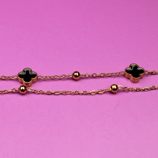 gold chain with clover-shaped charms on a pink background