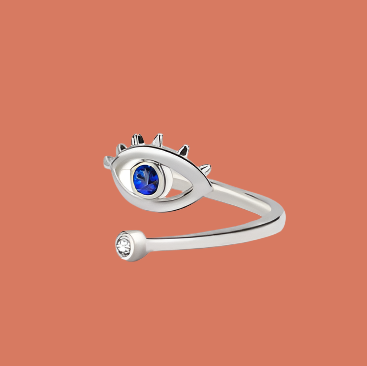 Silver ring with eye design and blue gemstone on a pink background