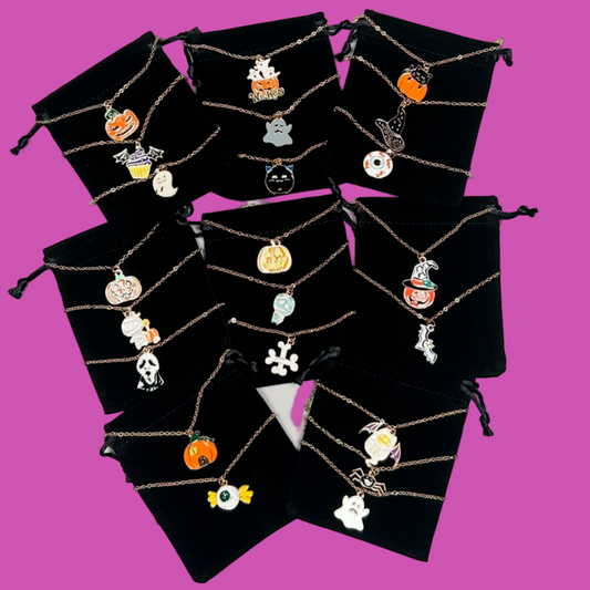 Collection of small necklaces with various pendants in black pouches on a gray background