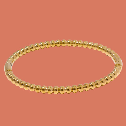 A gold-plated stainless steel bangle bracelet with a polished finish 