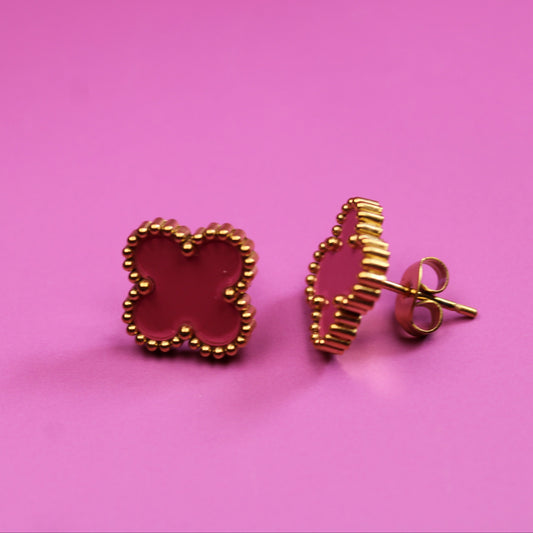 Gold butterfly-shaped earrings on a pink background