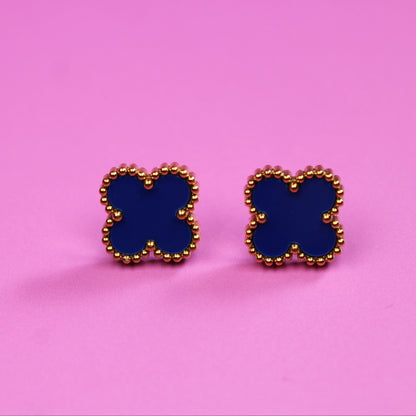 Butterfly-shaped earrings with blue centers and gold borders on a pink background