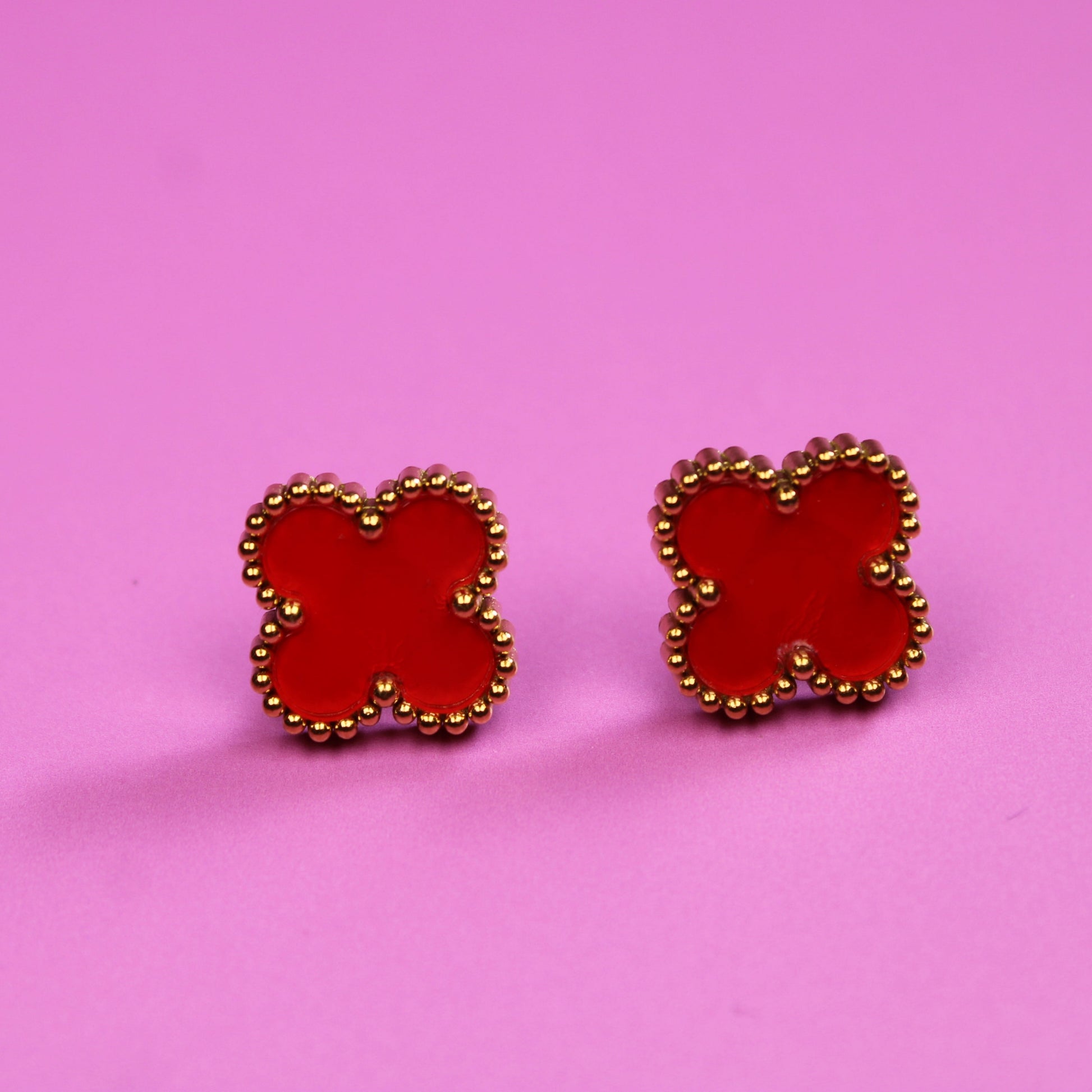 Red butterfly-shaped earrings on a pink background