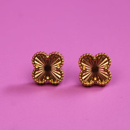 Gold butterfly-shaped earrings on a pink background