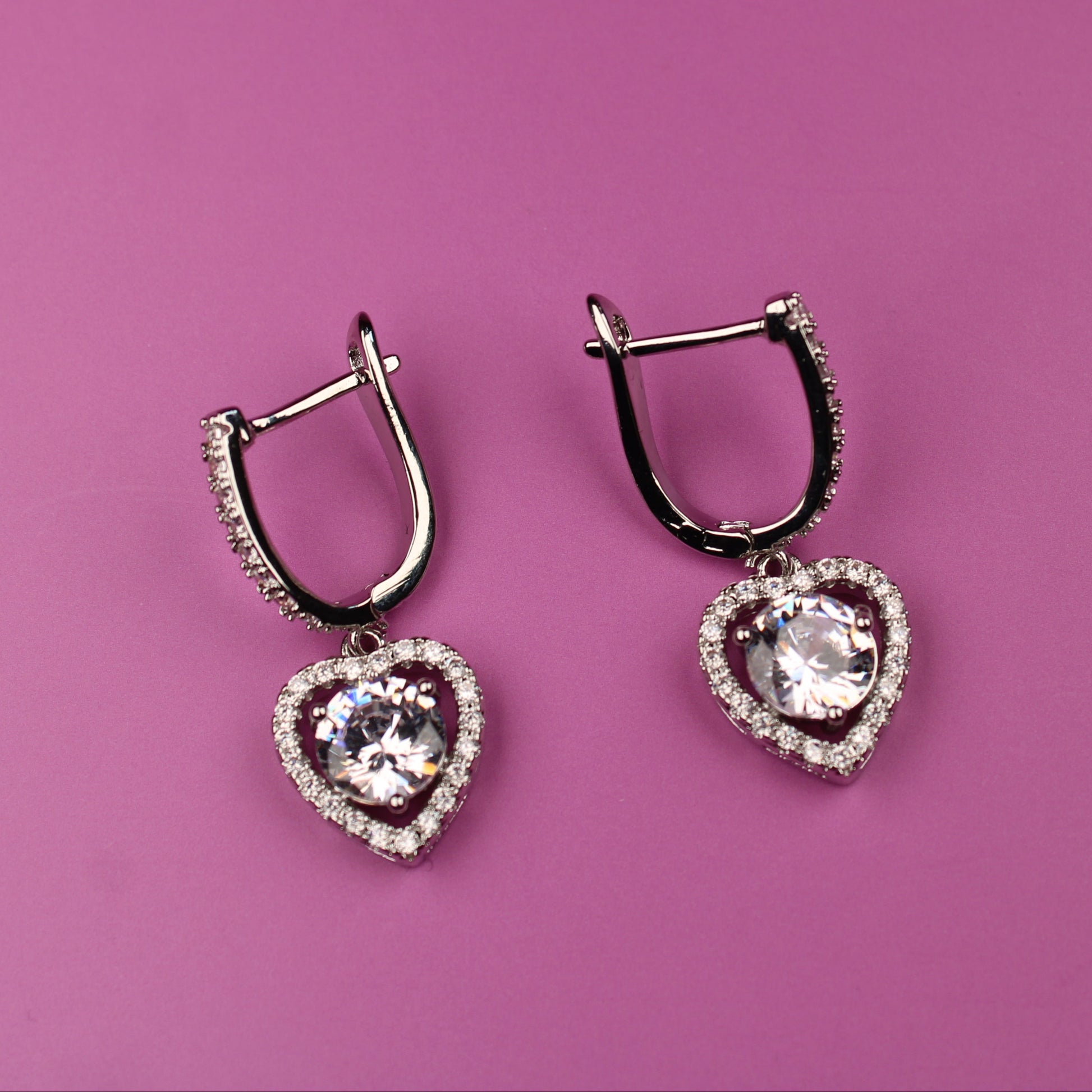 Heart-shaped earrings on a pink background