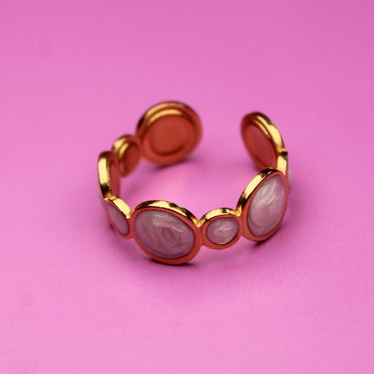 Gold ring with pink stones on a pink background