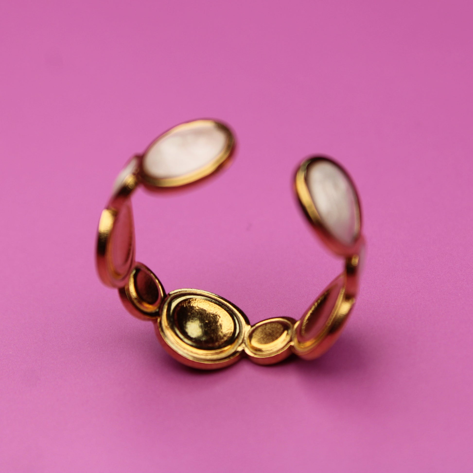 Gold ring with red stones on a pink background