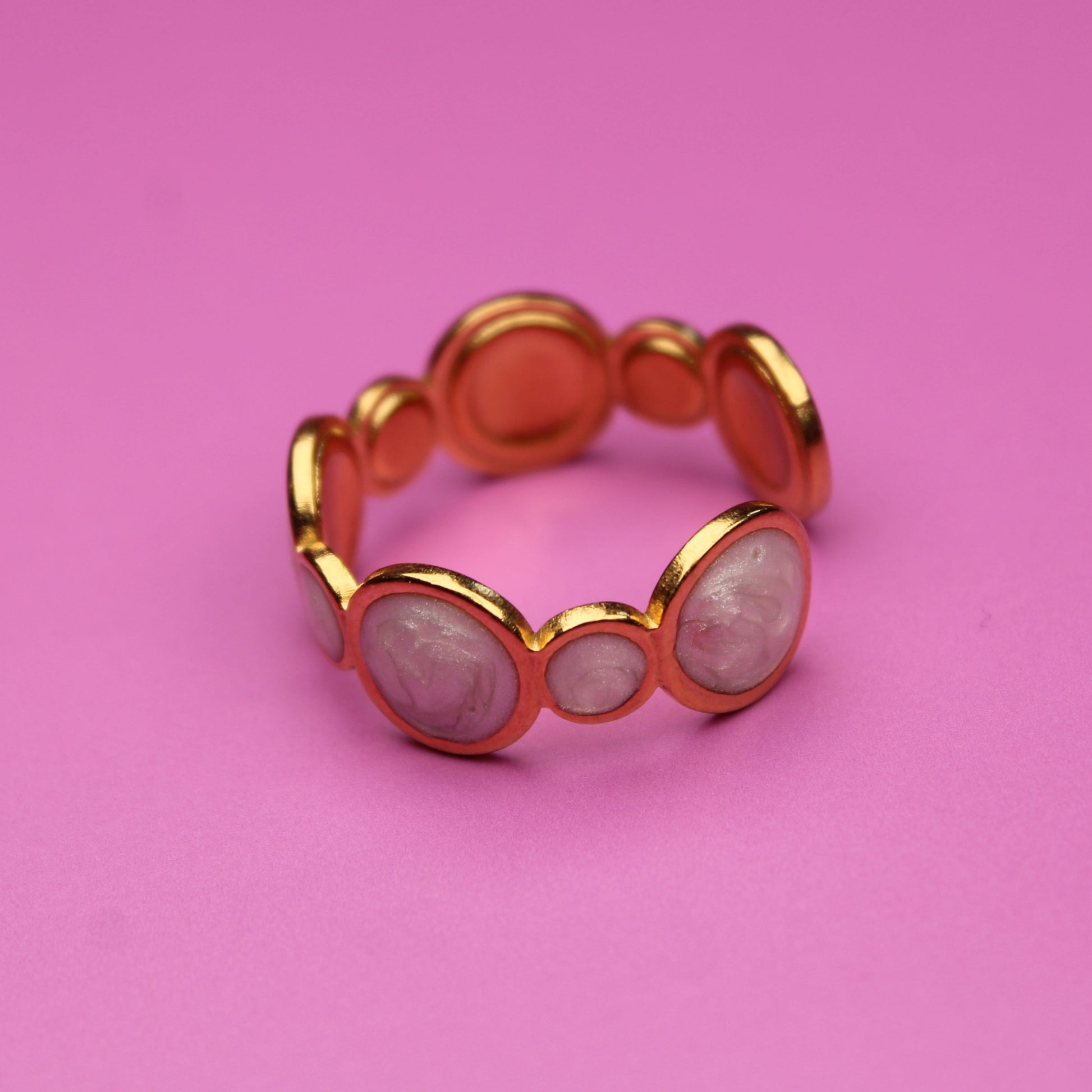 Gold ring with circular design on a pink background