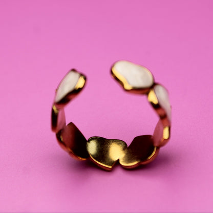 Gold ring with white stones on a pink background