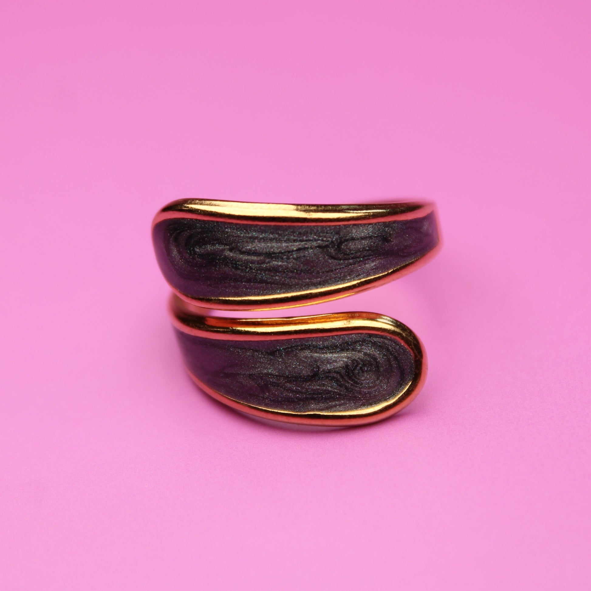 Black and gold ring on a pink background
