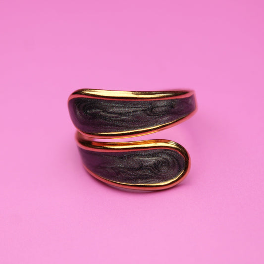 Black and gold ring on a pink background