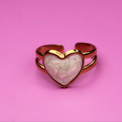 Heart-shaped ring with a pink stone on a pink background