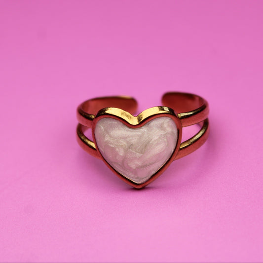 Heart-shaped ring with a pink stone on a pink background