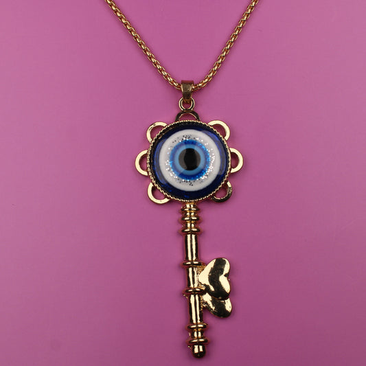 Gold key-shaped necklace with an eye pendant on a pink background